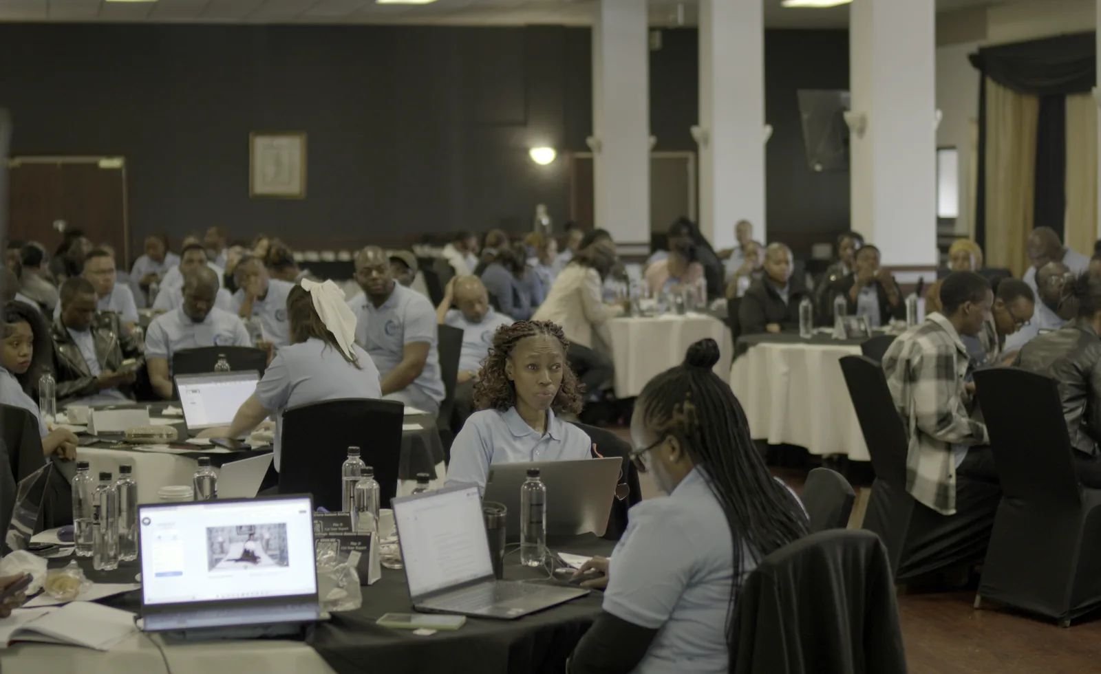 A full room of Sensation Global Holdings staff working on laptops at a business briefing.